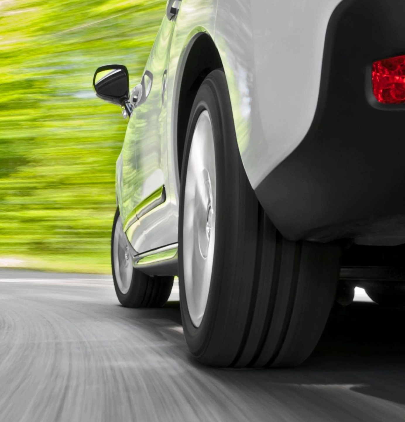 A car is driving down the street with its tires on.