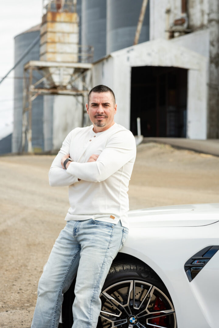 A man standing next to a white car.